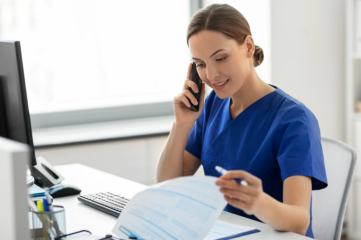 Care professional on the phone at a desk – symbolic image for MD Medicus care and rehabilitation management